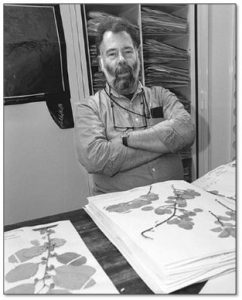 Black and white photograph of Les Mehrhoff with herbarium specimens
